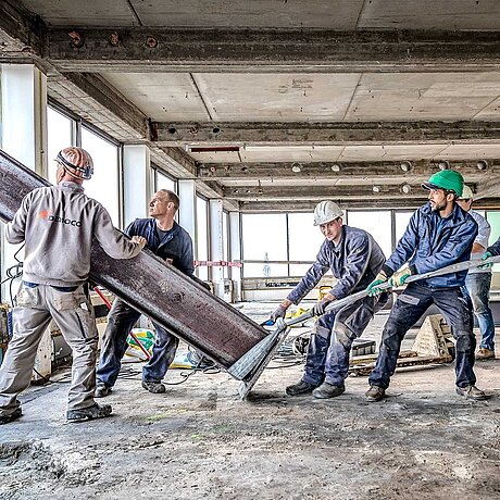 [Translate to Belgian Dutch:] Bouwvakkers trekken aan een stalen steun.